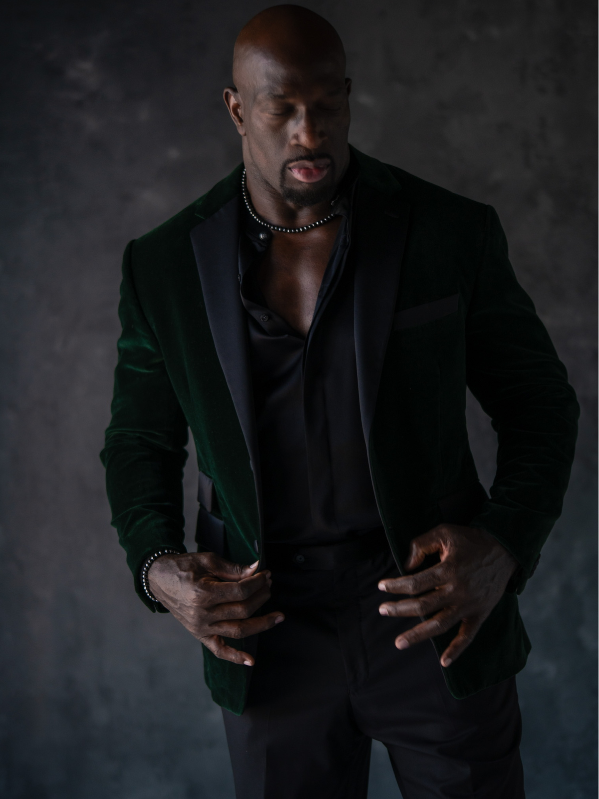 Titus O'Neil wearing a dark suit with a green velvet jacket and black diamond beaded necklace and bracelet